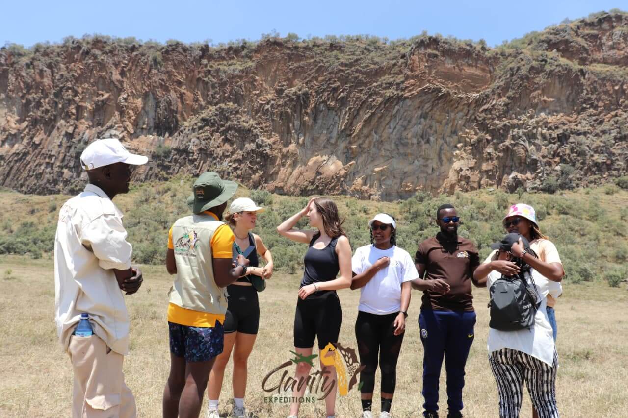 A guided group pauses at the base of dramatic rock cliffs